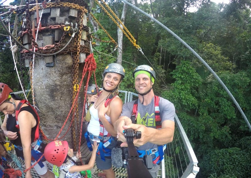 man and woman posing for camera on zipline platform