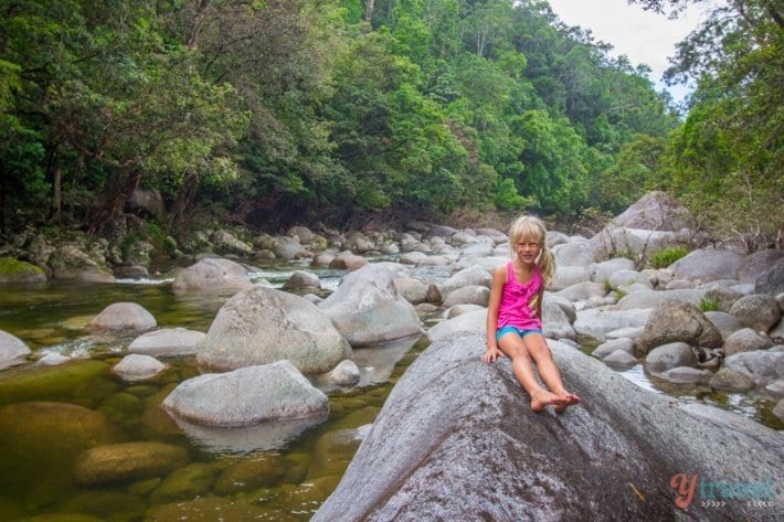 girl sitting on large boulder by the river 