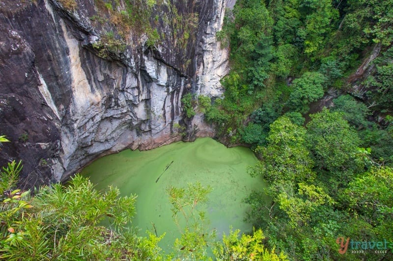 green pool of water surrounded by cliffs and lush forest. Hypipamee Crater, 