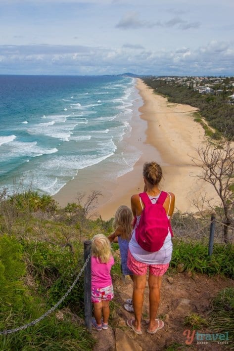 people standing on a mountain lookout facing the ocean