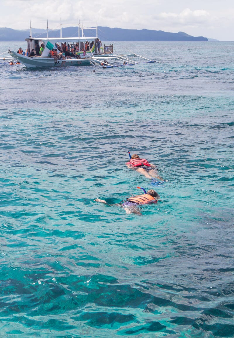 people snorkelling near a boat 