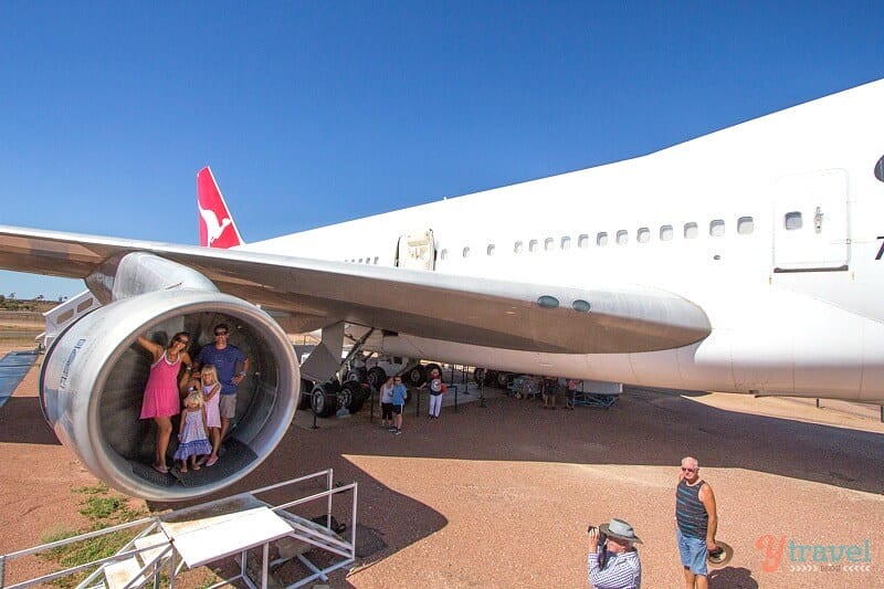 people standing inside plane engine on wing