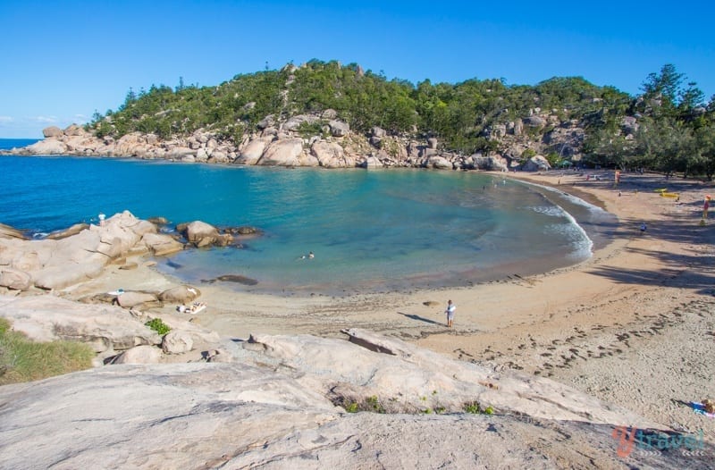 A sandy beach next to piles of rocks