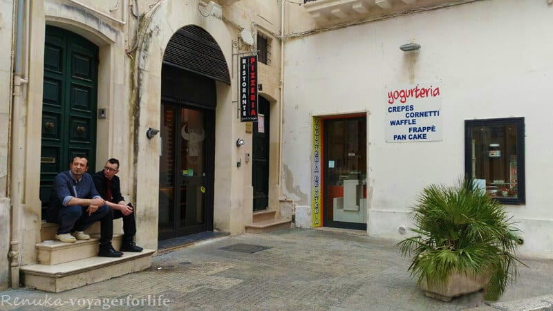 men sitting in doorway of buildings