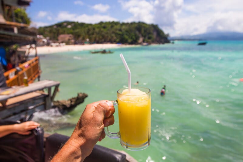 man holding lemon slushie on edge of water