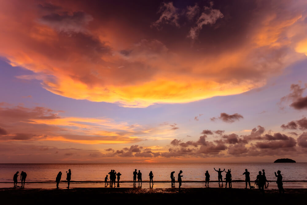 silhouettes of people by the shore enjoying a beach sunset