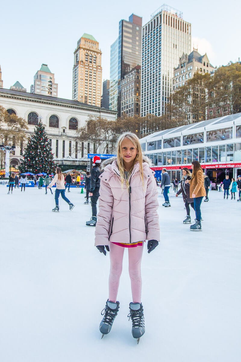 girl Ice skating at Bryant Park with skyline views in backgorund