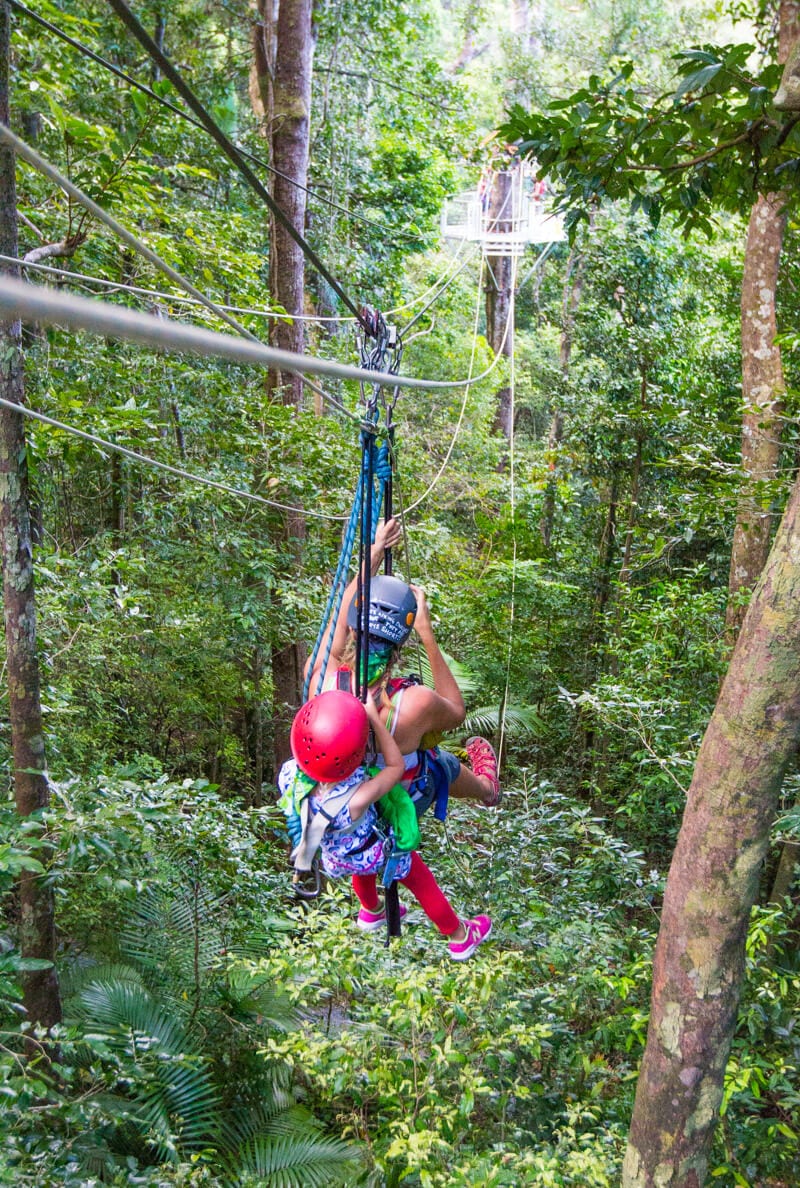 woman with girl on back ziplining