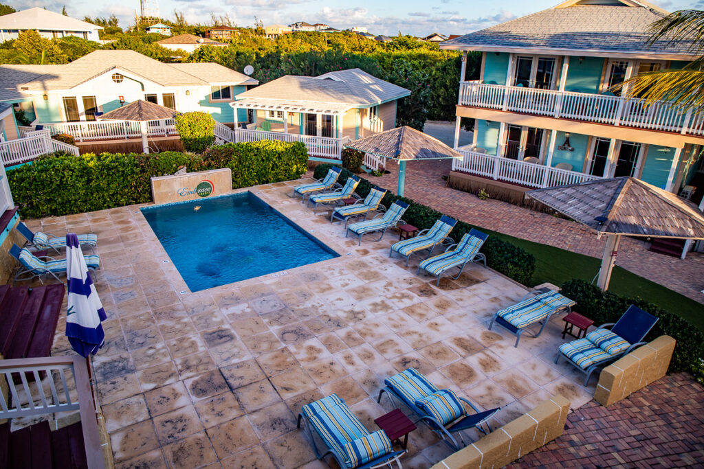 Resort swimming pool surrounded by pool chairs and villas