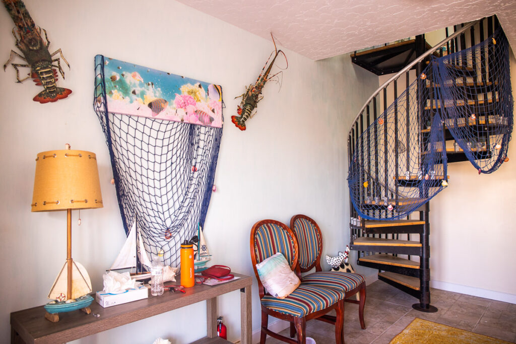 Entrance of a villa with chairs, fishing net, lamps, and spiral staircase