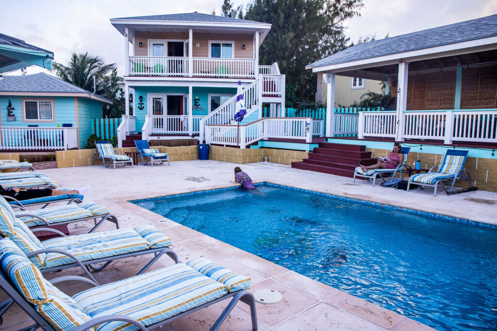 Pool chairs around a pool and 2 story villa in background