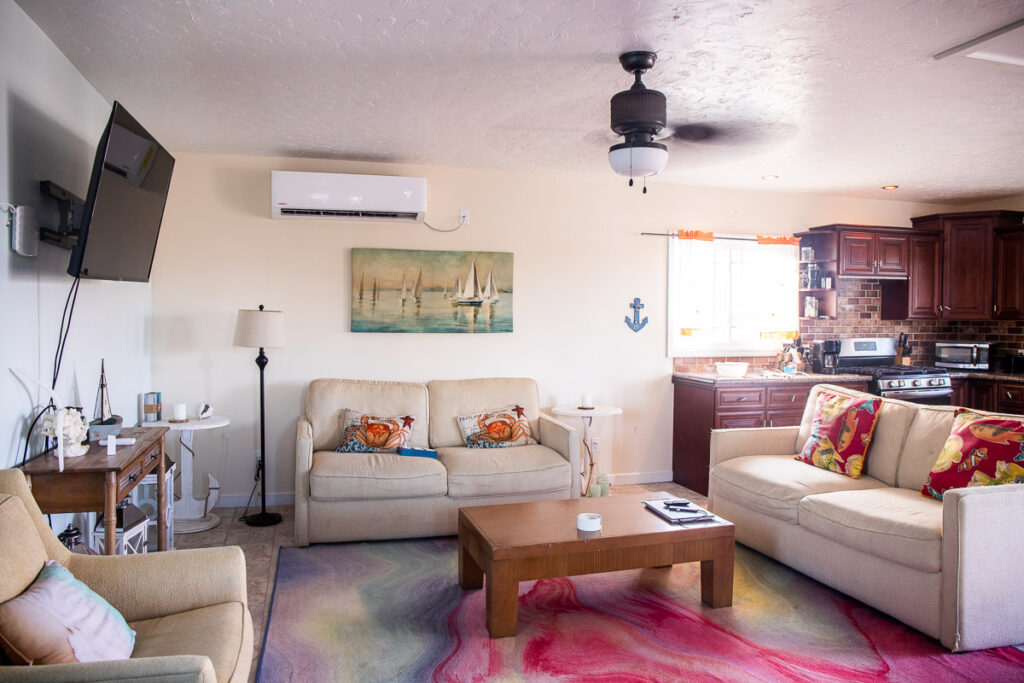 Coffee table, couches, tv and kitchen inside a villa