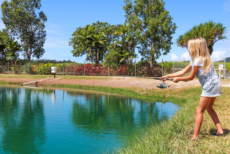 girl throwing a fishing line into pond