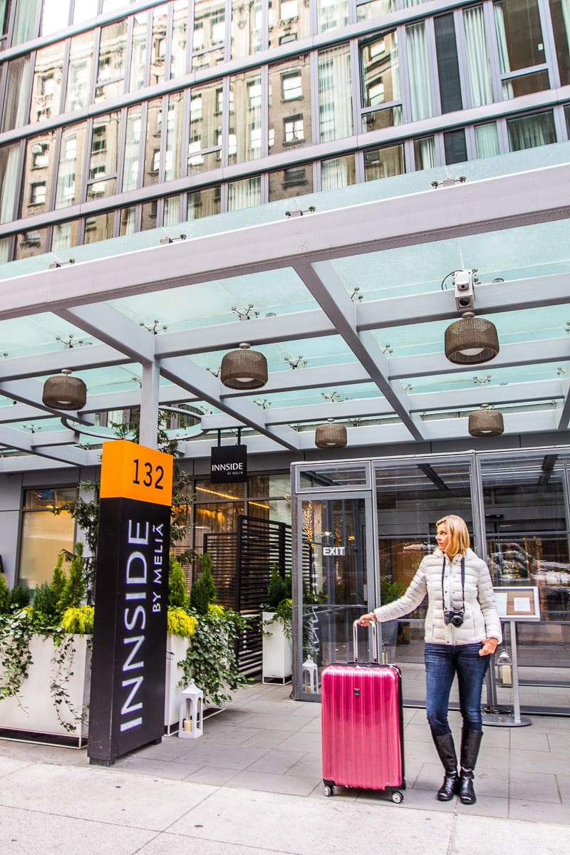 woman with suitcase standing outside innside new york nomad