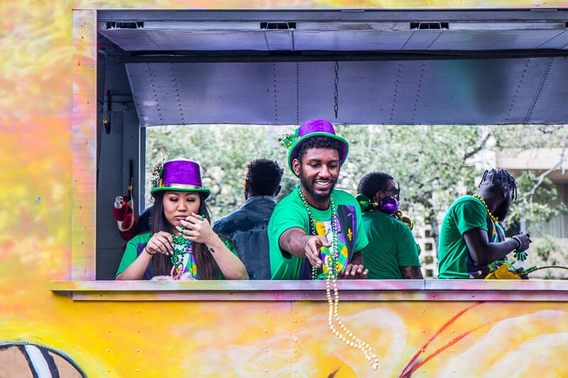 people  throwing beads to crowd from truck