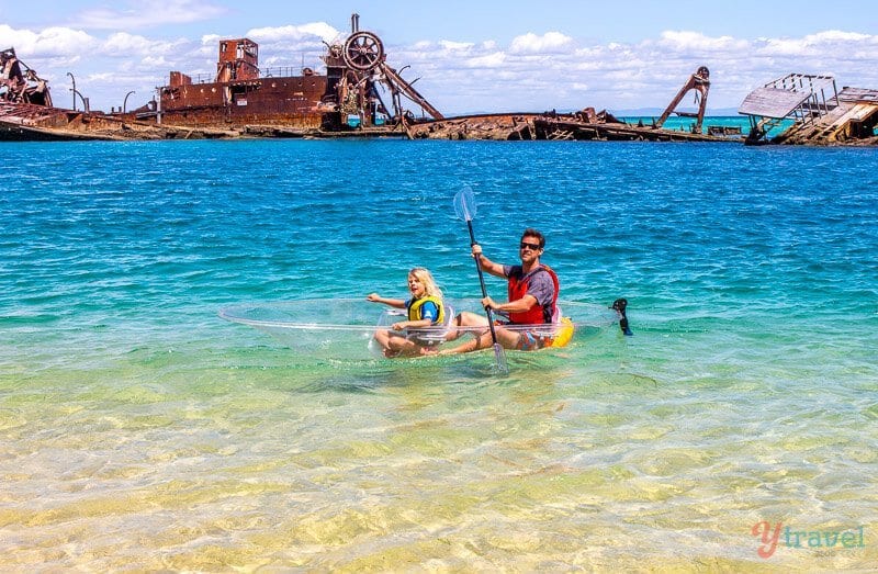 people in clear Kayak next to ship wrecks