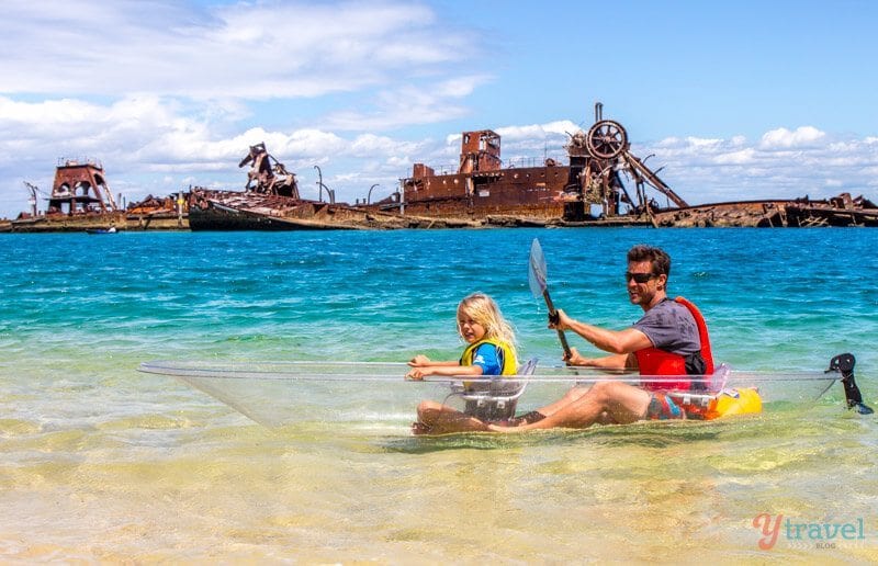 people in clear Kayak next to ship wrecks