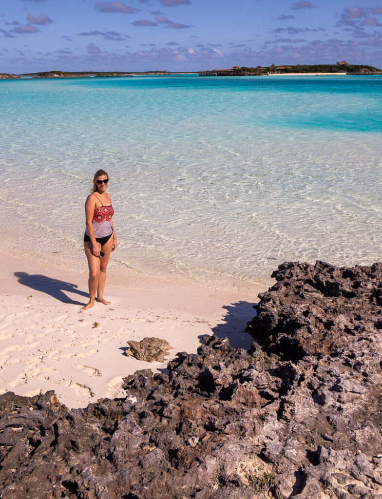 Lady standing at the edge of a beach with rocks in the foreground