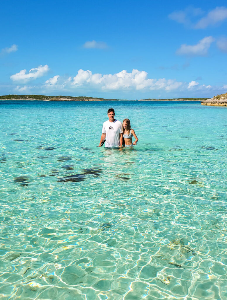 Father and daughter wading through aqua colored water