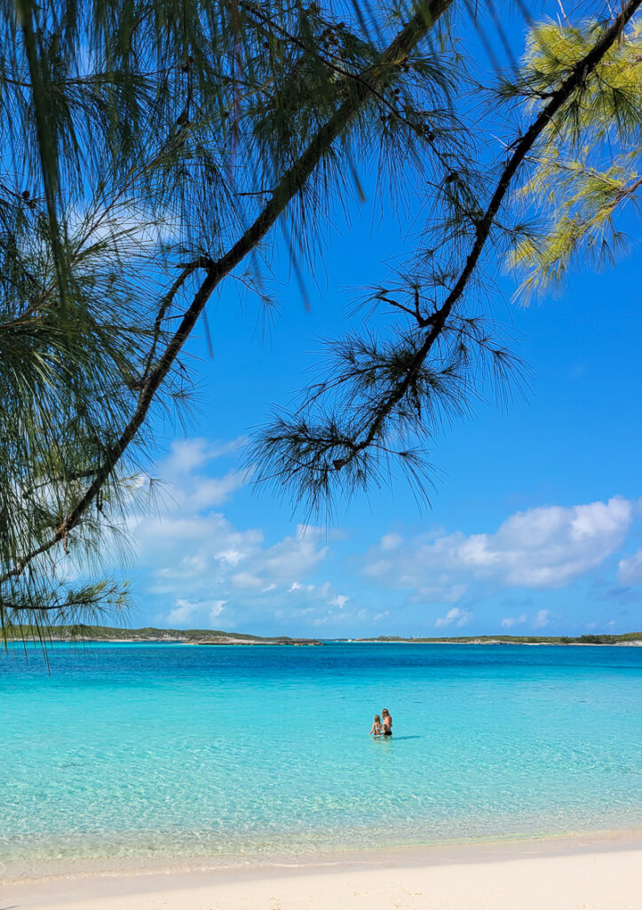 Two kids standing in waist deep water at a beach