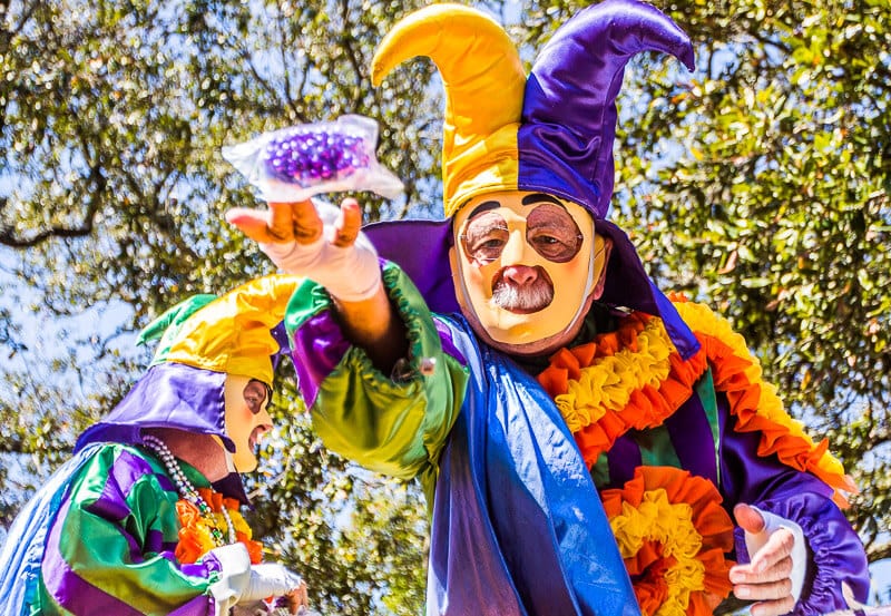 man in mardi gras costume throwing beads