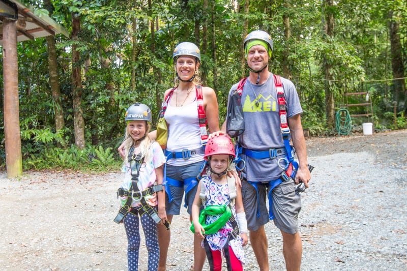 family dressed in zipline harness posing for camera