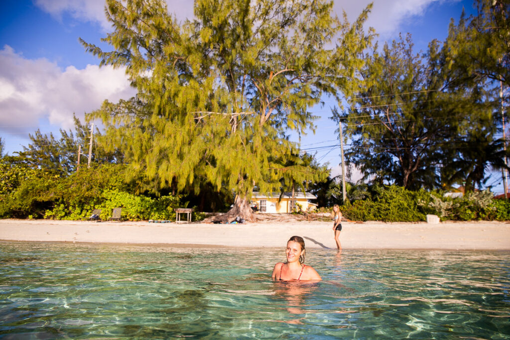 Woman swimming at the beach with trees behind her