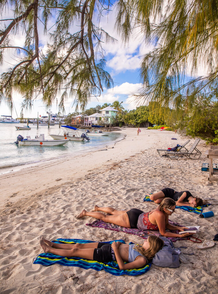 Mom and two daughters relaxing on a beach reading