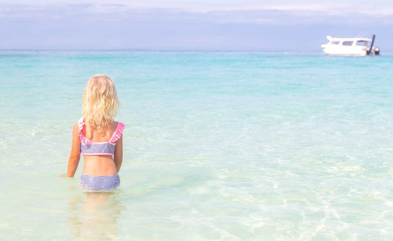 girl looking at boat in water at Punta Bunga Beach Boracay