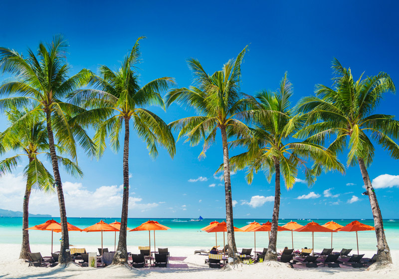 white beach lounge bar chairs and umbrellas on boracay tropical island in philippines