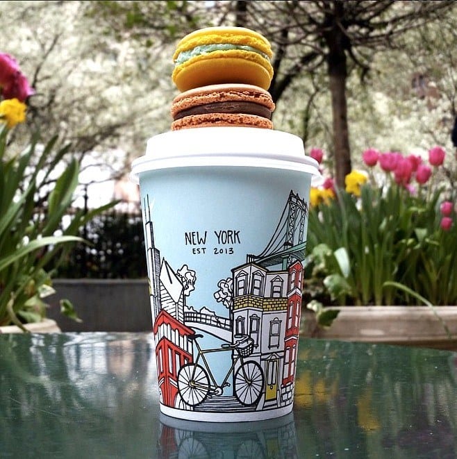 colored coffee cup on table with macarons on top