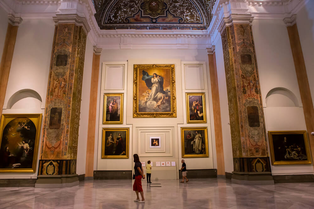 woman looking at paintings on wall in art gallery