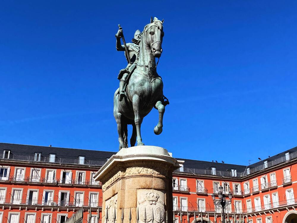 statue of man on horse in front of red buildings