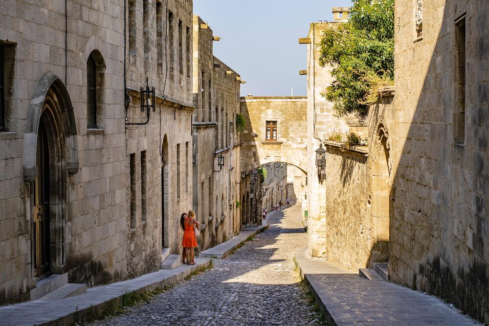 person walking on cobblestone Rhodes Street of Knights