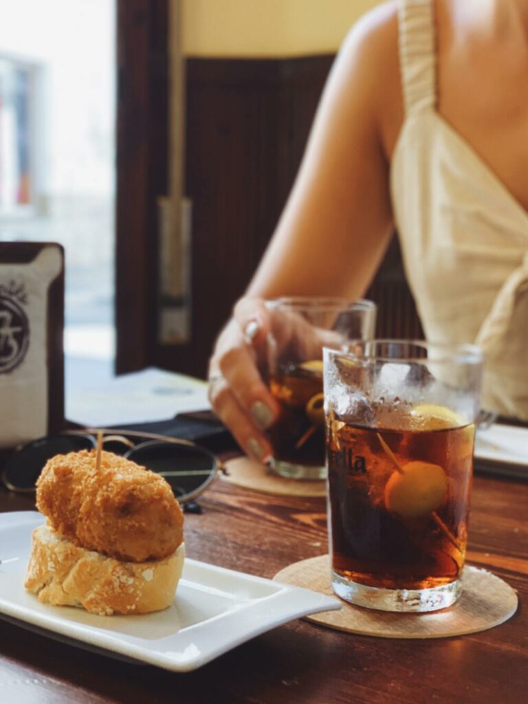 person sitting at table with drinks and tapas