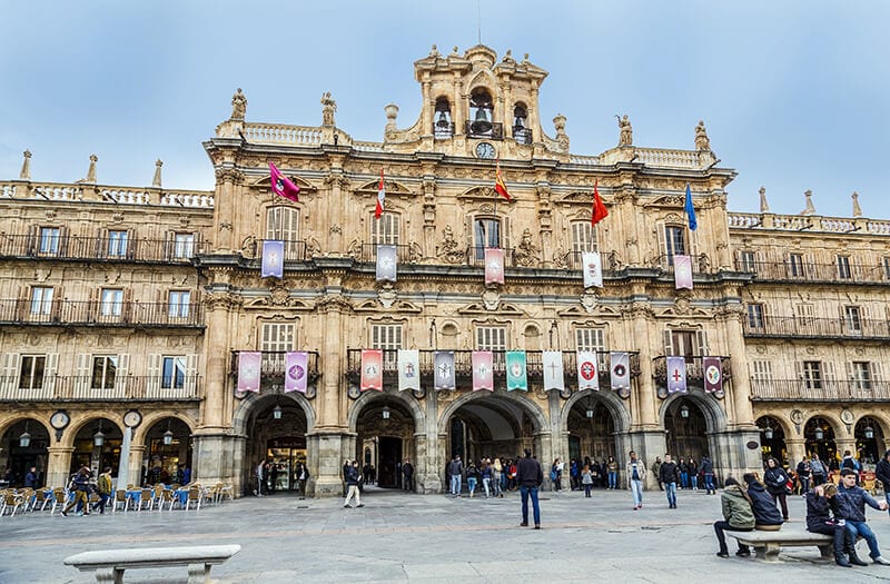 historical building on plaza with peopel milling about