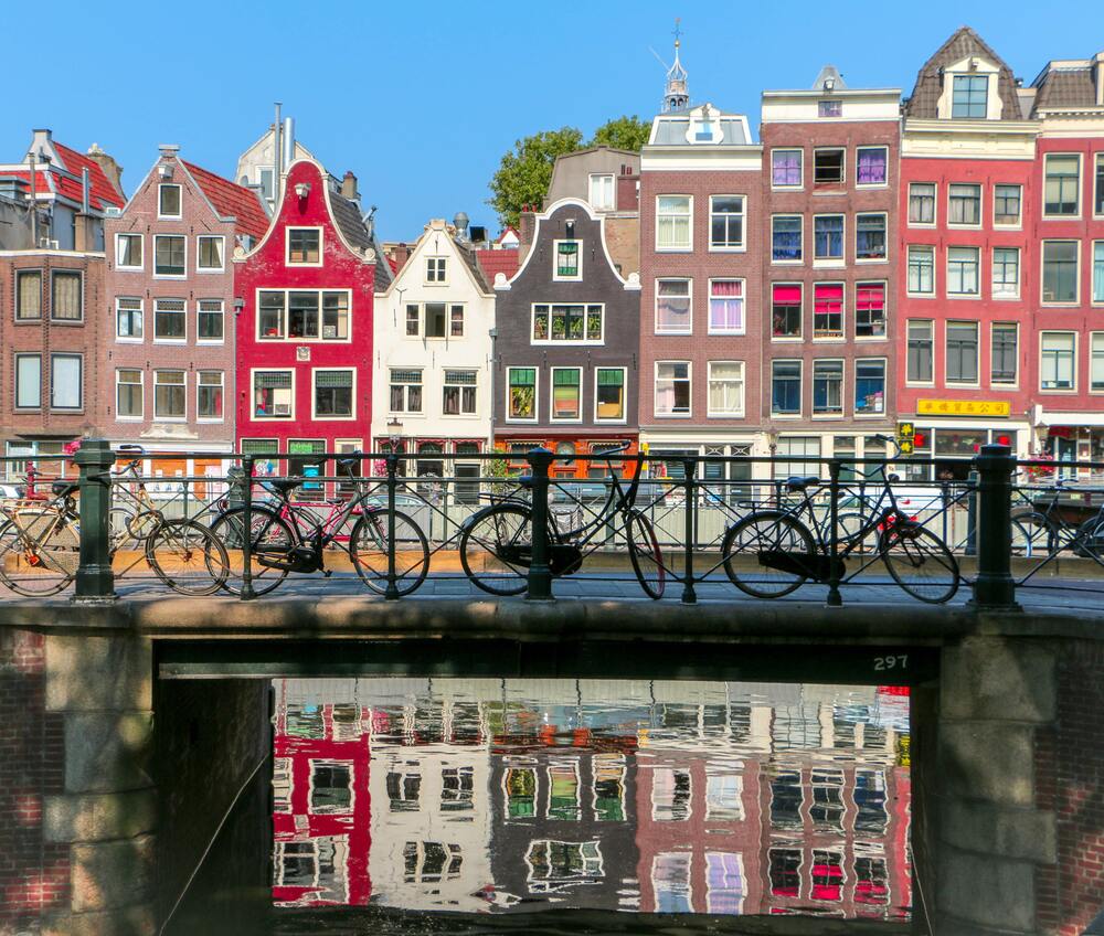 bikes lined up on path in front of colorful buildings on the canal 