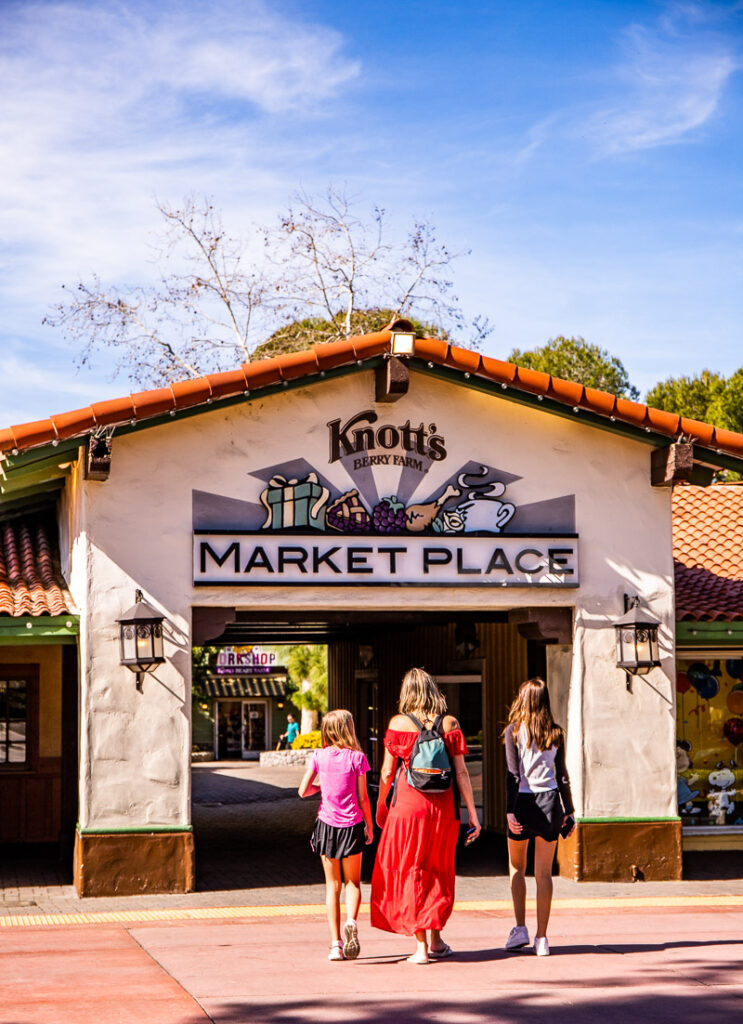 Mom and two daughters walking across a street to the entrance to a marketplace