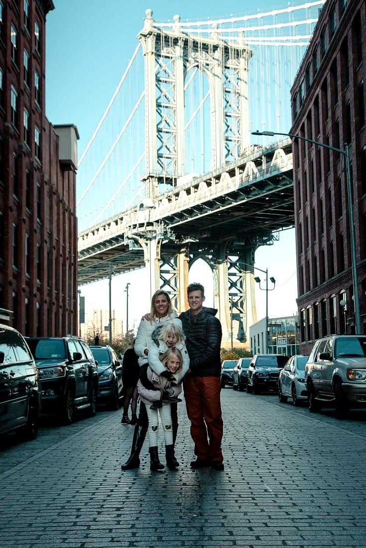 family standing on cobblestone road with manhattan bridge behind them