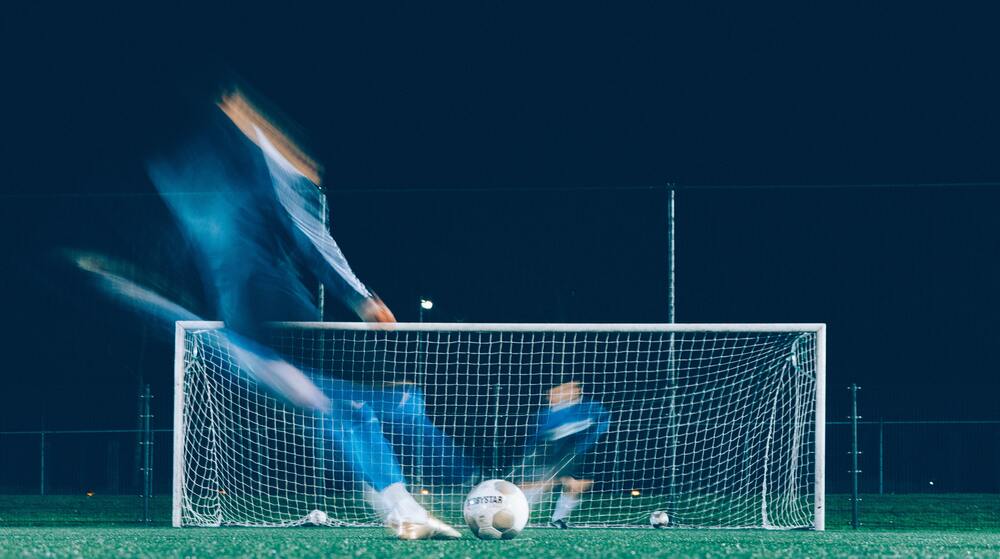 men kicking soccer goal