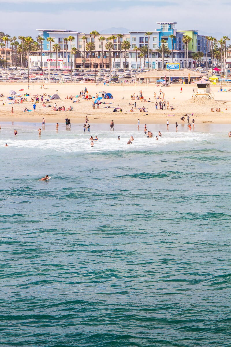 looking at Huntington beach from the water with people on the sand and colorful buildings