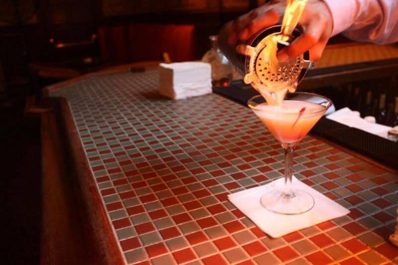 person pouring cockatil on bar