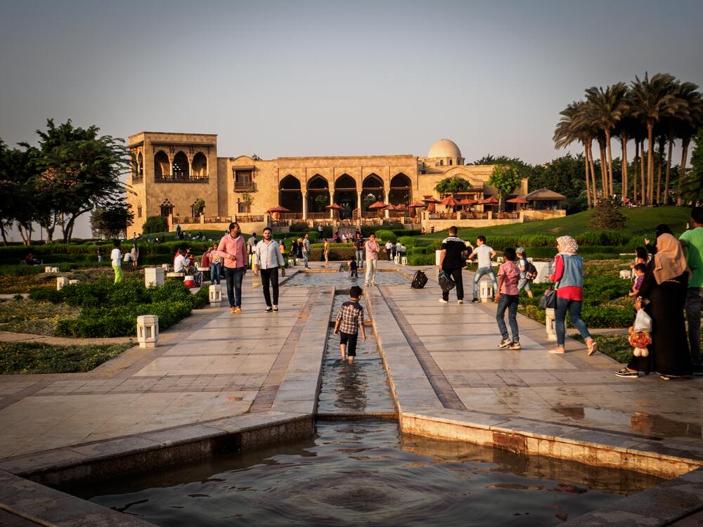 people walking beside water channel at al azhar park 