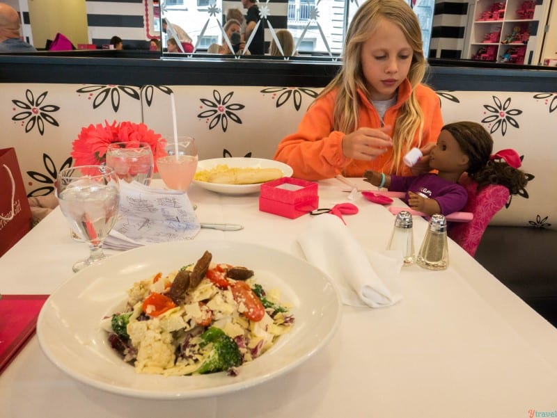 girl feeding american girl doll in cafe