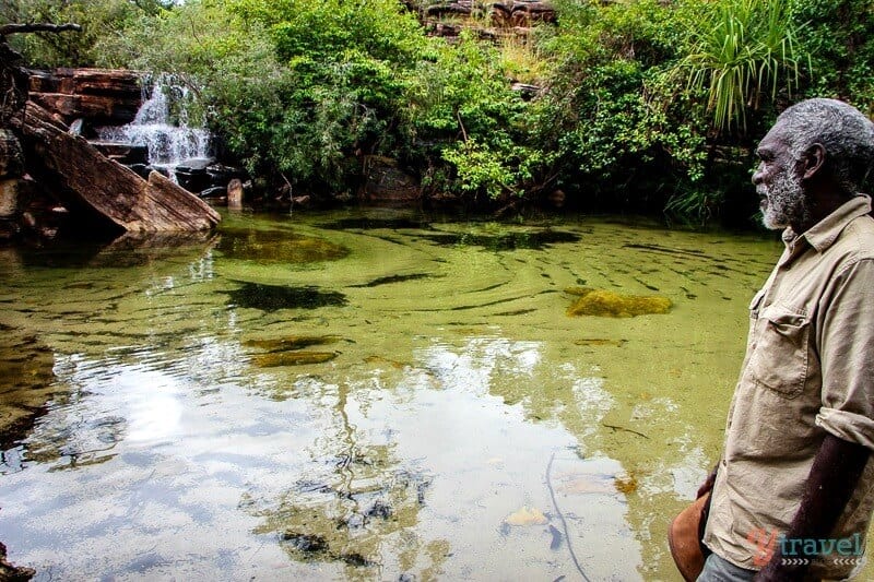 Aboriginal elder looking into clear pool of water in Arnham Land 