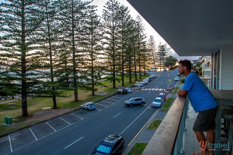 man standing on balcony looking at beach view