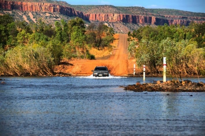 car driving across the road covered in water 