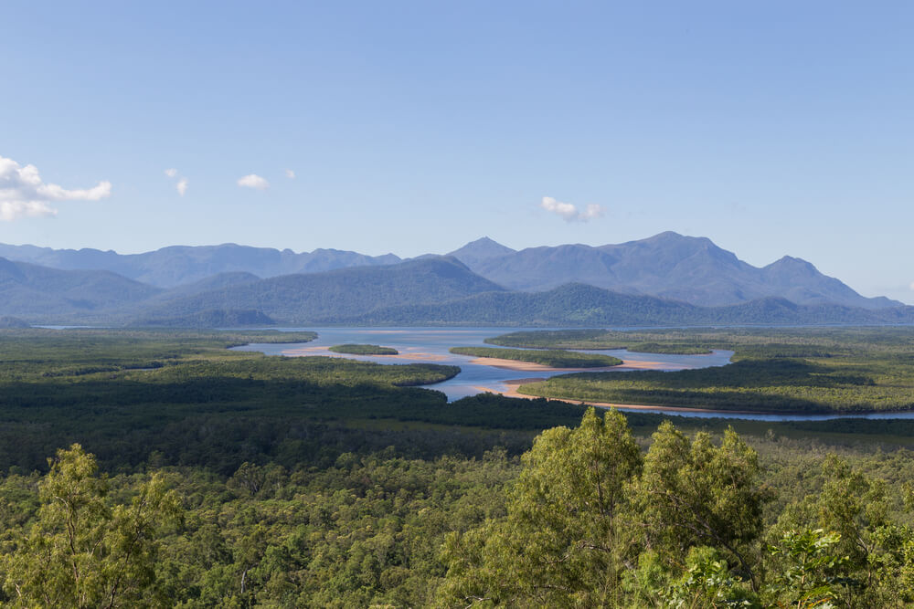 view of river winding through green valley and mountains in background