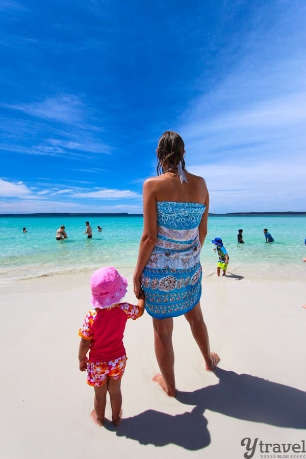 a woman holding a childs hand on beach