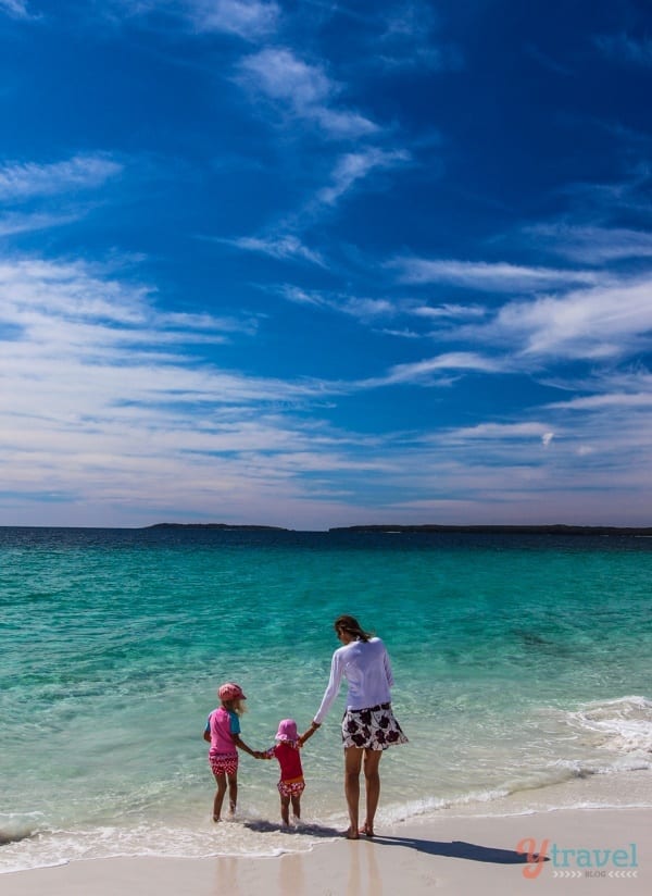 a woman and kids holding hands while standing in the ocean